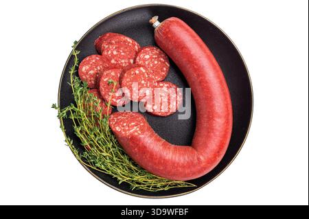 Sucuk turco intero e a fette (sujuk) con timo su un piatto nero. Salsiccia piccante e stagionata, isolata su bianco Foto Stock