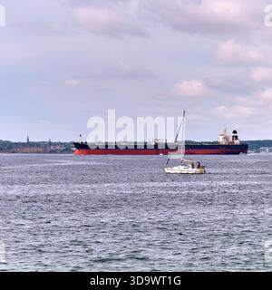 HELSINGBORG, Skåne län, SVEZIA - 12 agosto 2025: Una vista sul mare a Helsingborg Svezia presenta una grande nave petroliera e una barca a vela sull'acqua Foto Stock