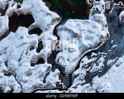 Vista dall'alto di un paesaggio naturale astratto di formazioni innevate e di un fiume ghiacciato in una remota natura selvaggia durante la stagione invernale Foto Stock