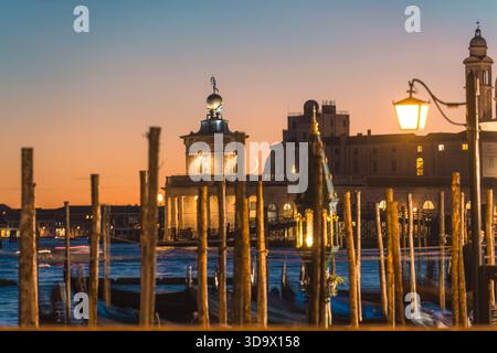 Vista serale della Basilica di Santa Maria della salute con lampioni illuminati e gondole ormeggiate sul Canal grande di Venezia Foto Stock