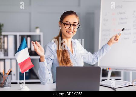Insegnante che coinvolge gli studenti in una lezione virtuale con una bandiera francese sullo sfondo Foto Stock