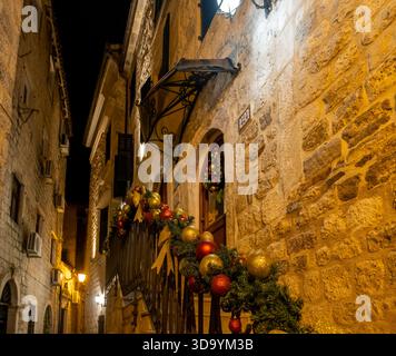 ghirlanda natalizia con ornamenti rossi e dorati che adornano il balcone dell'edificio a Cattaro Foto Stock