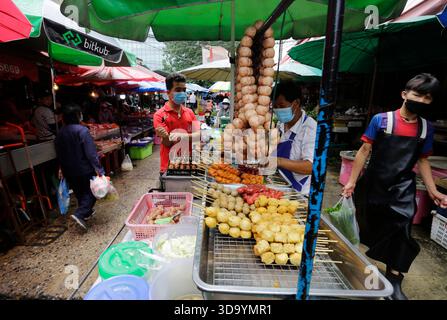 Bangkok, Tailandia - 15 luglio 2022: Il venditore vende spiedini di maiale e pollo nel mercato di Khlong Toei in mezzo a un aumento dell'inflazione. Foto Stock