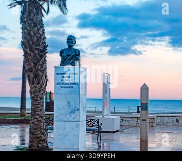 Un busto in marmo monumento a José Millán Jiménez ("El Carrerista") sul lungomare di Fuengirola. Presenta l'oceano e un suggestivo cielo crepuscolo. Foto Stock
