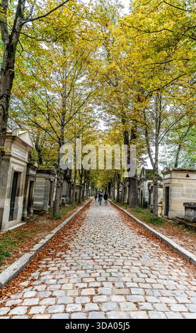 Scorcio di viale alberato con ciottoli nel monumentale Cimitero di Pere Lachaise, il più grande cimitero di Parigi, in Francia Foto Stock