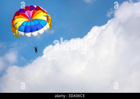 Parapendio con paracadute sullo sfondo di cielo nuvoloso blu. Foto Stock