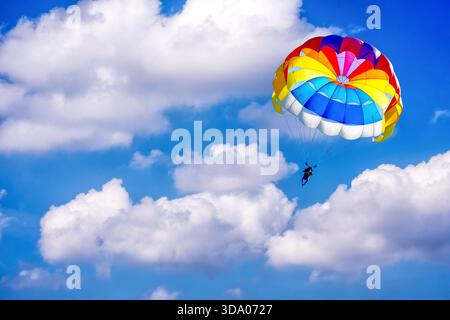 Parapendio con paracadute sullo sfondo di cielo nuvoloso blu. Foto Stock