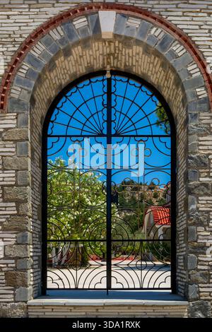 Porta decorativa in ferro battuto con arco di pietra e cornice blu con architettura del paesaggio mediterraneo Foto Stock