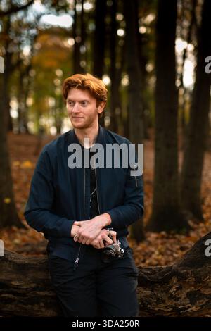 Un giovane ama passeggiare in una foresta mentre tiene in mano una macchina fotografica Foto Stock