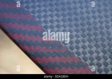 Primo piano del tessuto geometrico. lo sfondo in tessuto testurizzato mostra un motivo a rombi blu con bordo rosso a chevron, tappezzeria moderna ed elegante desi Foto Stock