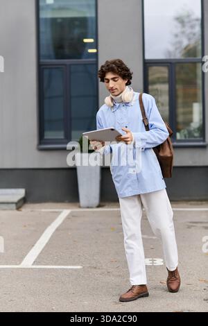 Un uomo giovane e affascinante con i capelli ricci, passeggia all'aperto con un abito elegante, esplorando la città. Foto Stock