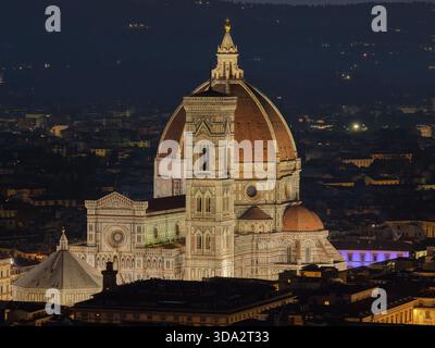 Cattedrale di Firenze (Santa Maria del Fiore) illuminata di notte, vista da un lungo teleobiettivo che mette in risalto la cupola, la facciata e il campanile di Giotto Foto Stock