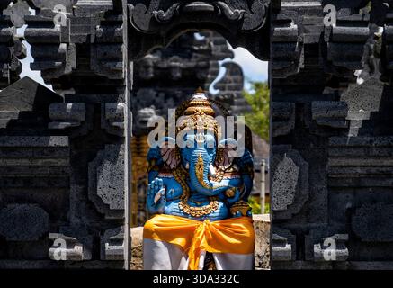 Una vibrante statua blu di Ganesha incorniciata da ornate architetture in pietra. Foto Stock