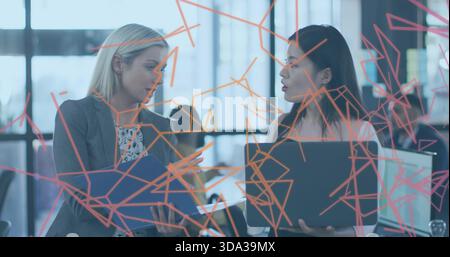 Parla di una donna con cartellino blu in un blazer grigio e di una collega con un notebook in ufficio vicino alle decalcomanie arancioni Foto Stock