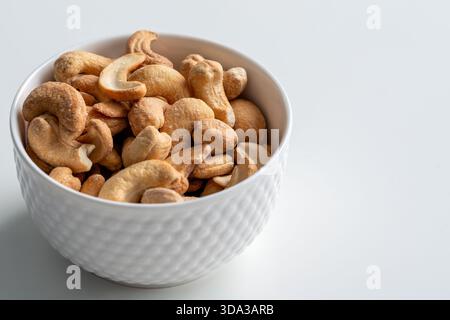 Ciotola di anacardi arrostiti su sfondo bianco Foto Stock