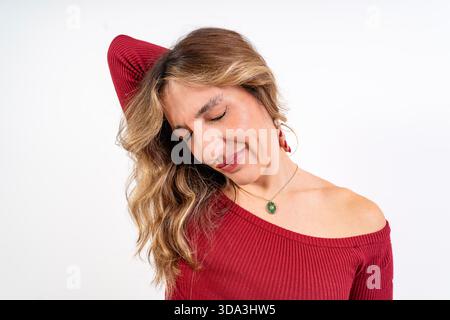 Giovane donna che inclina la testa, allunga i muscoli del collo, chiude gli occhi con disagio Foto Stock