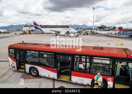 Scena dell'aeroporto con un autobus navetta rosso e bianco in primo piano, con un aereo LATAM parcheggiato sullo sfondo. José Joaquín de Olmedo Internat Foto Stock