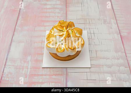 Fetta di torta al limone servita in un vaso di vetro, con strati di biscotti tritati, crema al limone e una meringa svizzera con p dorata Foto Stock