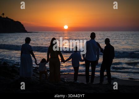 Sagome di una famiglia che si tiene per mano e guarda il tramonto a Palos Verdes, CA Foto Stock