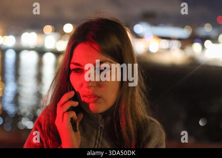 Giovane donna che riceve una chiamata urgente con luce rossa Foto Stock