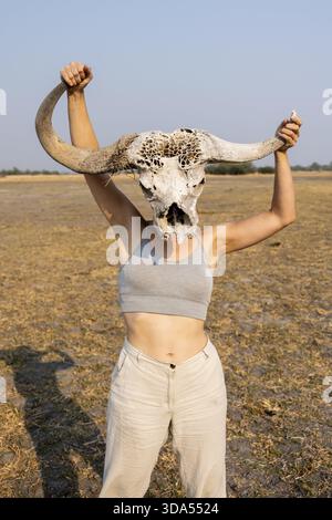 Giovane donna con teschio di bufalo davanti alla testa, Lustig, Botswana Foto Stock