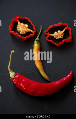 Faccia divertente sorridente fatta con peperoncino caldo su sfondo ardesia nera Foto Stock