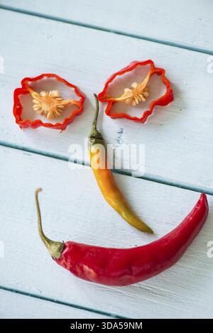 Faccia divertente e sorridente fatta con peperoncino caldo sul tavolo di legno Foto Stock
