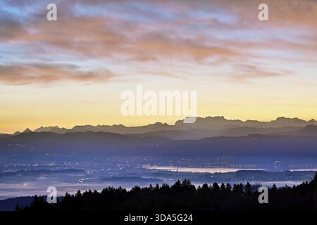 Vista dall'Horben del lago Zug con la città di Cham e Zug, dietro di esso le montagne innevate Fluebrig e Vrenelisgaertli alla luce dell'alba, BEI Foto Stock