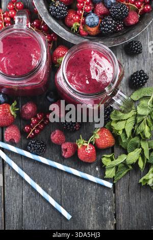 Frullato estivo di frutti di bosco in barattolo mason su un tavolo in legno rustico Foto Stock