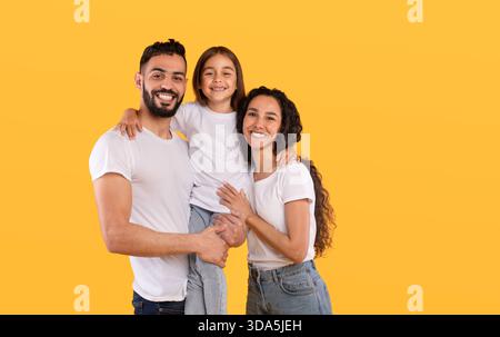 Happy Family in posa insieme su uno sfondo giallo brillante con Smiles e Joy Foto Stock