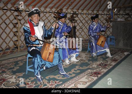 Musicista mongola riproduzione di morin khuur e indossando abiti tradizionali, Mongolia Foto Stock