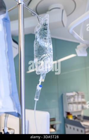 Infusione endovenosa in primo piano somministrata a un paziente durante l'intervento chirurgico in una sala operatoria sterile, che mostra le apparecchiature mediche e la cura intraoperatoria del paziente. Foto Stock