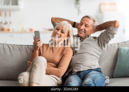 Coppia che si diverte a divertirsi insieme mentre guarda qualcosa su uno smartphone a casa Foto Stock