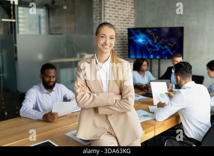 Giovane imprenditrice di successo che conduce con fiducia una riunione aziendale nell'ufficio moderno Foto Stock