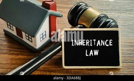 Concetto di legge sull'eredità su lavagna con martelletto e casa in miniatura su legno Foto Stock