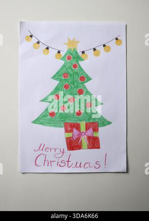 Foto ravvicinata del disegno del bambino. Albero di Natale decorato con ghirlanda, stella e regalo, con il messaggio buon Natale! Simbolo di spi festivo Foto Stock