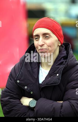 Donna con una giacca a piumino e fascia rossa con un'espressione sottile Foto Stock