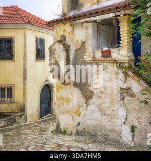 Uno stretto vicolo a Sinarades, un vecchio villaggio con autentici edifici in pietra tradizionali, un gatto che riposa in un secchio, Corfù, Isole Ionie, Grecia Foto Stock