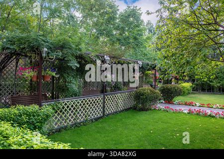 Un bellissimo giardino europeo con recinzioni verdi, prati, alberi, cespugli. Foto Stock