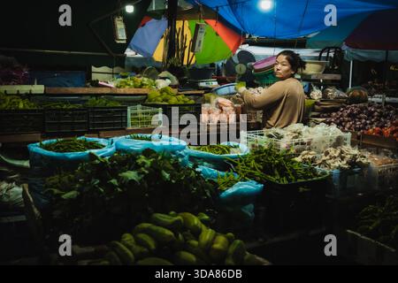 Paro, Bhutan - 17 settembre 2025: Vista di un venditore tra le vivaci sfumature di prodotti freschi sotto il baldacchino del mercato, un ricco arazzo della vita quotidiana. Foto Stock