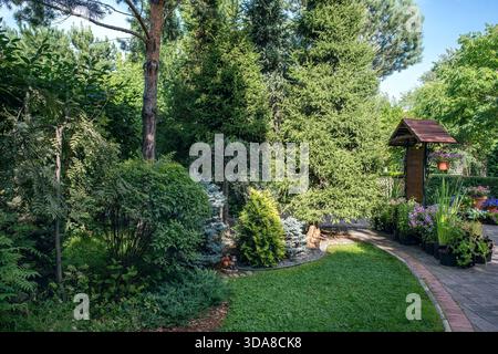 Un bellissimo giardino europeo con recinzioni verdi, prati, alberi, cespugli. Foto Stock