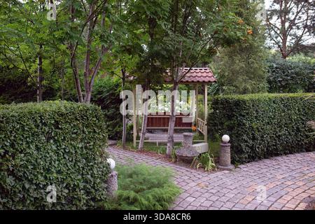 Un bellissimo giardino europeo con recinzioni verdi, prati, alberi, cespugli. Foto Stock