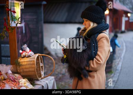 Örebro, Närke - Svezia, 12-09-2025 donna con un cane nero della pomerania al mercatino di natale di Wadköping. Foto Stock