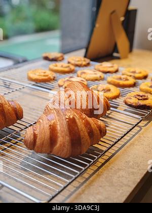 Nizza, Francia – 22 marzo 2025: Croissant dorati appena sfornati e biscotti artigianali esposti su scaffali refrigeranti all'interno della vetrina del famoso Phil Foto Stock