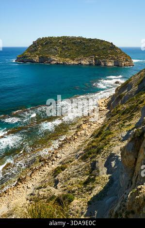 Isola dell'Isla del Portitxol e onde che si infrangono sulla riva dalle scogliere della spiaggia di Portichol (Jávea, Marina alta, Alicante, Mar Mediterraneo, Spagna) Foto Stock