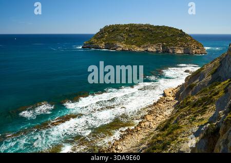 Isola dell'Isla del Portitxol e onde che si infrangono sulla riva dalle scogliere della spiaggia di Portichol (Jávea, Marina alta, Alicante, Mar Mediterraneo, Spagna) Foto Stock