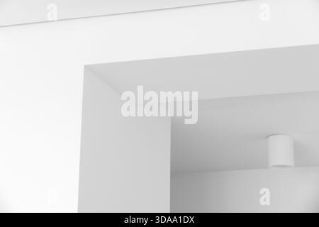 Interni architettonici sereni e bianchi con angoli nitidi, illuminazione soffusa e spazi aperti. L'ambiente minimalista enfatizza l'umore calmo e le linee pulite Foto Stock