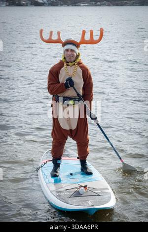 Un uomo in costume da renna su un paddleboard all'evento di Santa Palooza del 2025 a Greenwood Lake, Ocean County, New York. Foto Stock