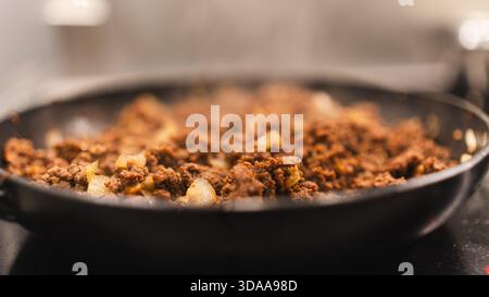 Cottura di manzo macinato con cipolle in una padella, presentato splendidamente. Sfrigolanti, saporiti e pronti per piatti di tacos, pasta o riso. Cucina casalinga Foto Stock
