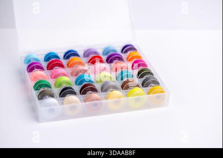 La scatola contiene molti steli di filettatura in colori brillanti per cucire. Foto Stock